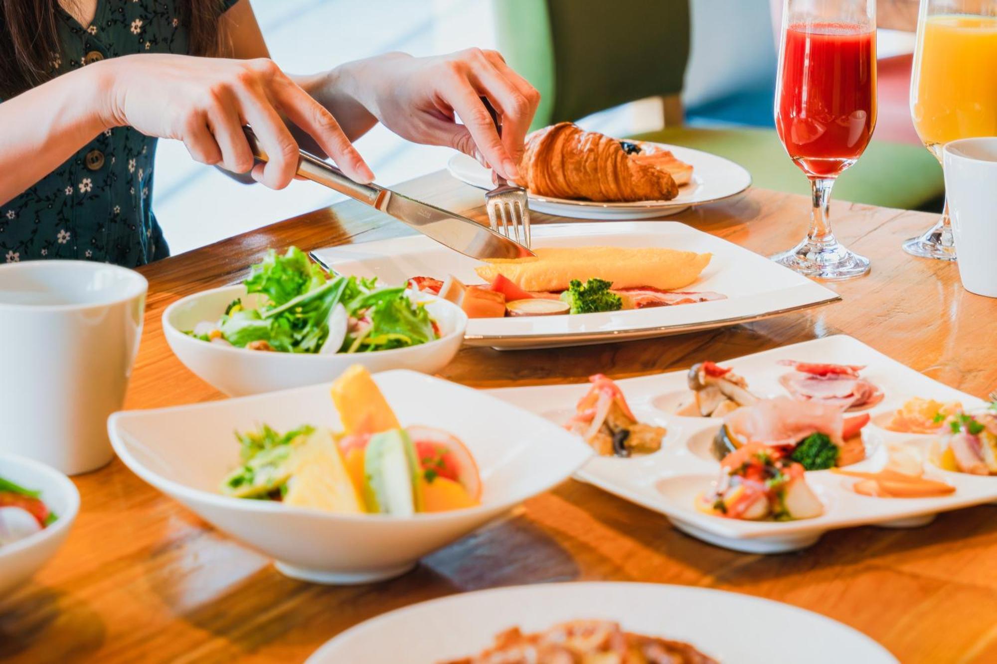 金泽日航酒店 外观 照片 A woman using a knife and fork to eat a croissant